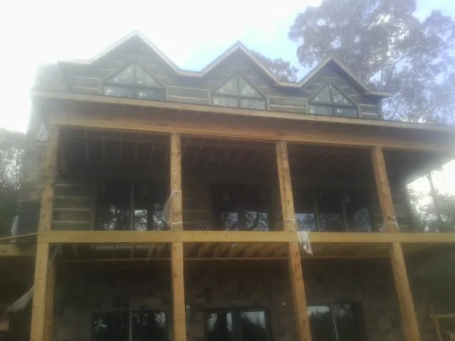 Dormers and porch framing on a large log home under construction — Roof Coating work by our crew in Canaan